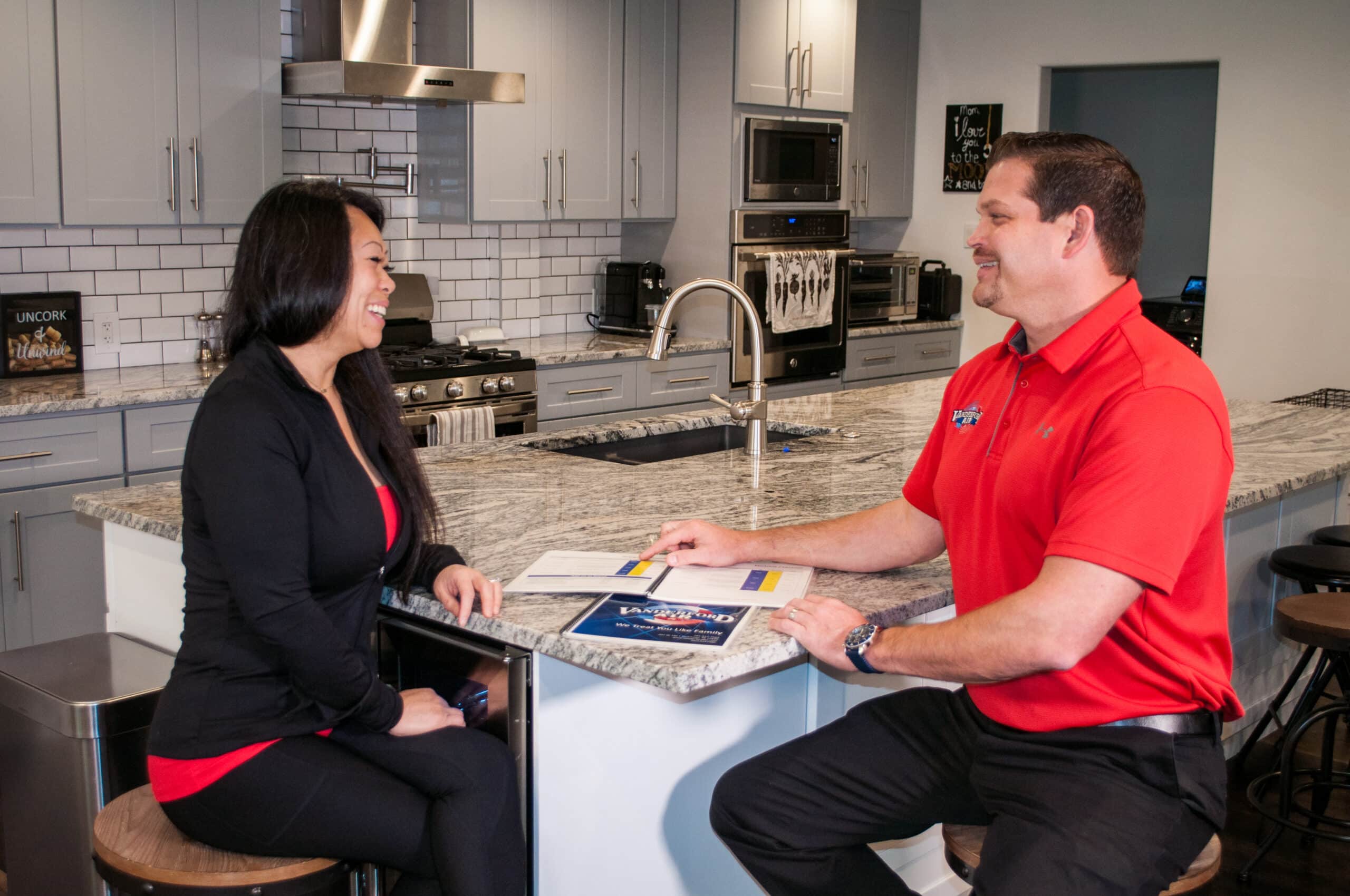 Vanderford Air and Plumbing technician sitting with a homeowner at her kitchen counter, going over air conditioning repair and replacement options
